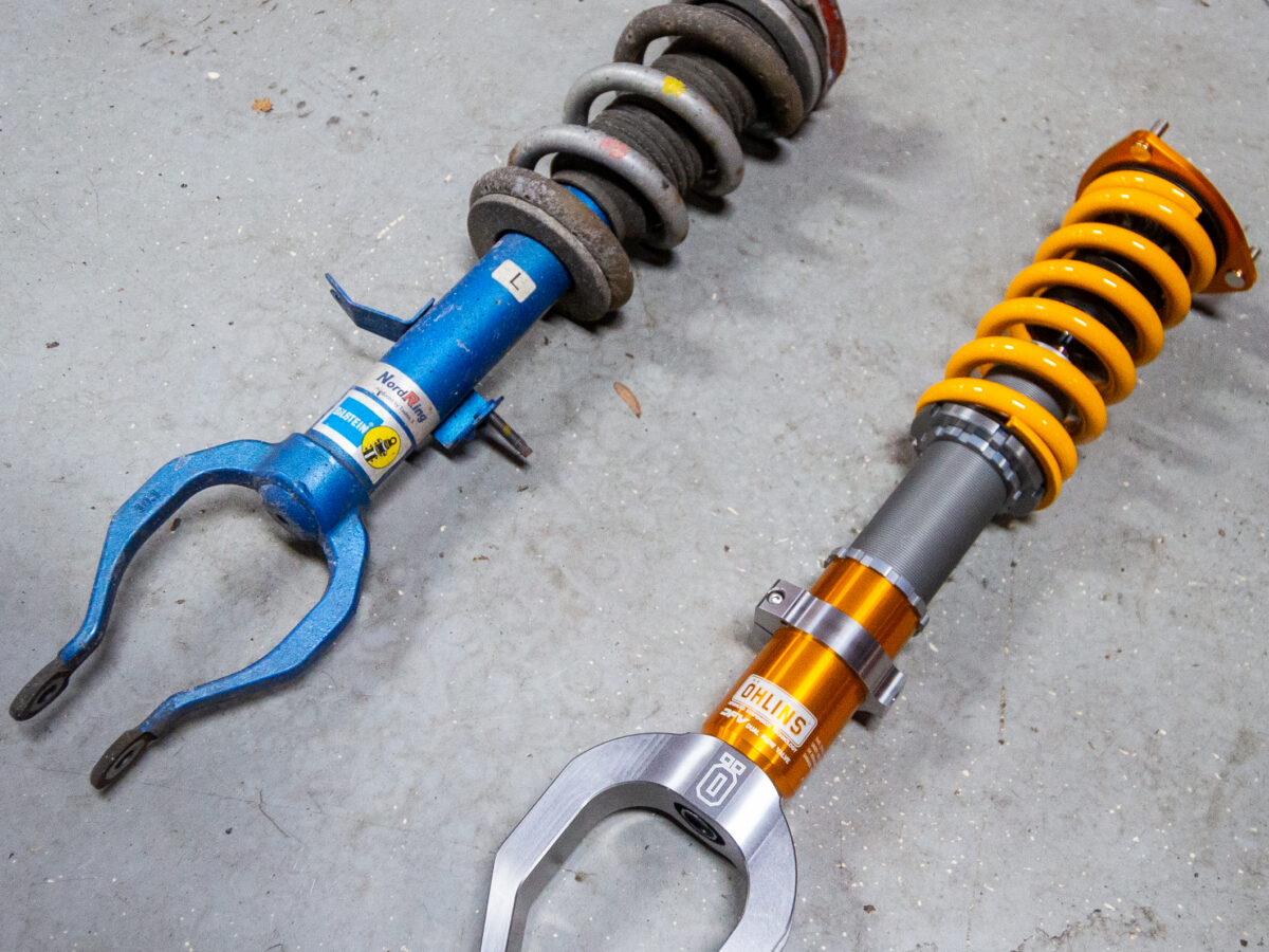 Old blue coilover and new yellow coilover side by side on a concrete floor.