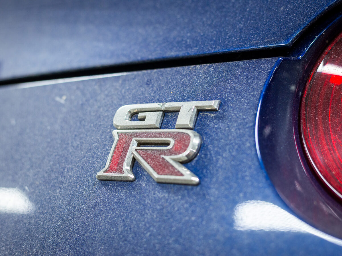 Close-up of GT-R badge on a blue car with a red taillight visible.