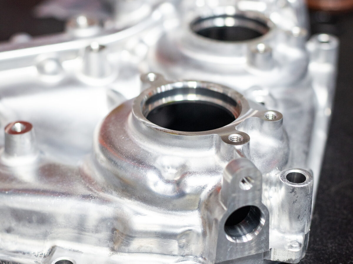 Close-up of a polished metal car engine part with multiple openings on a dark surface.