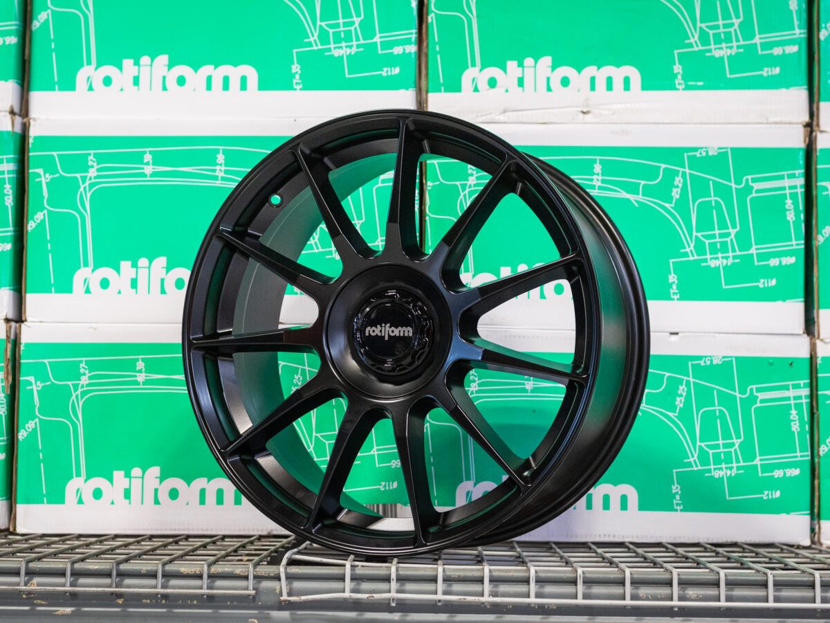 Black Rotiform wheel displayed against stacked green Rotiform boxes.