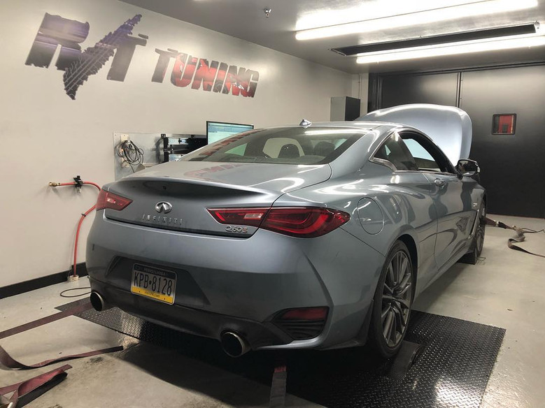 Silver Infiniti Q60S on a dyno in a tuning shop, hood open, R/T Tuning logo on the wall.