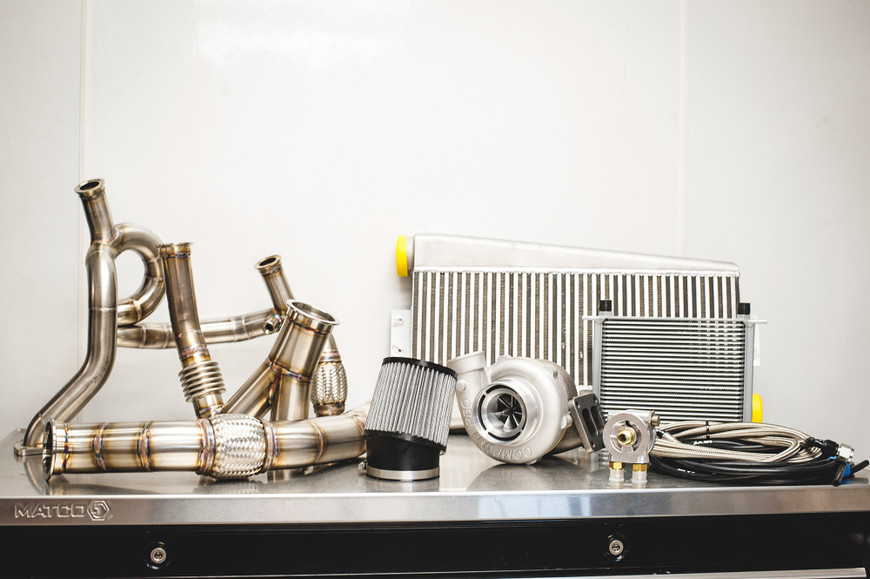 Turbo kit components including pipes, intercooler, air filter, and CT4X 6267 Comp Turbo on a metal surface.