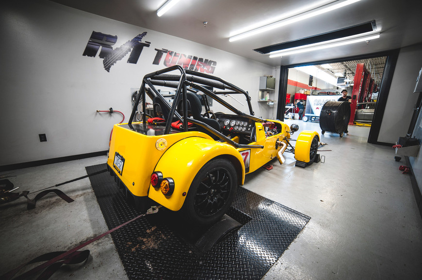 Yellow MNR VortX car on a dyno in a tuning garage, with a technician and equipment in the background.