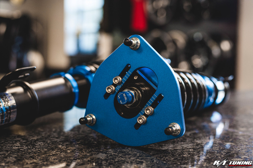Blue Revel Coilover by Tanabe on a Subaru STi, featuring adjustable camber plate and spring assembly on a workshop table.