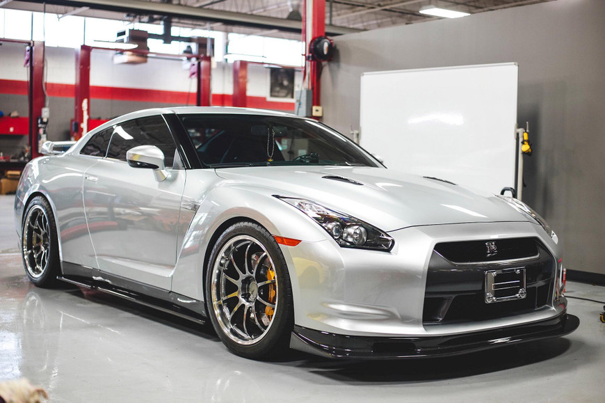Silver sports car with tinted windows in a garage, surrounded by red and gray walls.